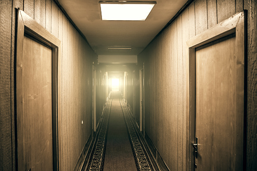 Empty corridor in apartment building with doors and light in the end of hall, perspective, vintage toned