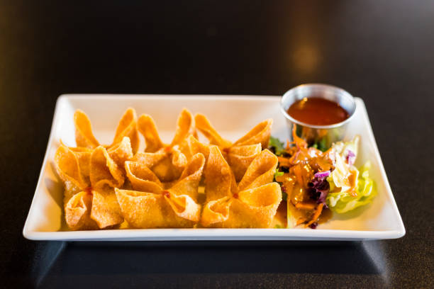 Crab Rangoon on Tray A tray of crab wontons with a side salad and sweet chili dipping sauce. yangon photos stock pictures, royalty-free photos & images
