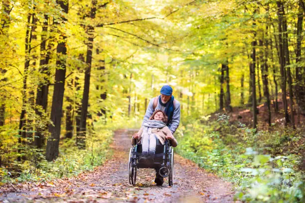 Photo of Senior couple with wheelchair in autumn forest.