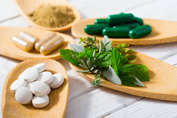 Medicines herbal leaves, ground herb powder and medicament pills on bamboo spoons, white wooden table nutritional supplement photos stock pictures, royalty-free photos & images