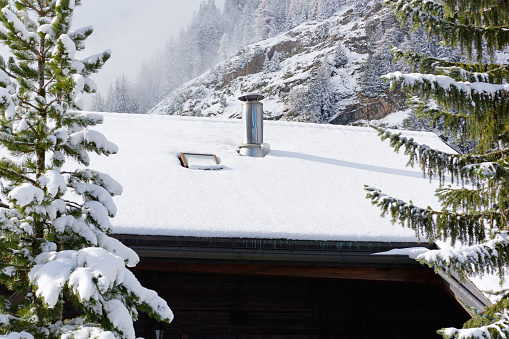 CLose-up of the smoke stack at snow roof in winter.