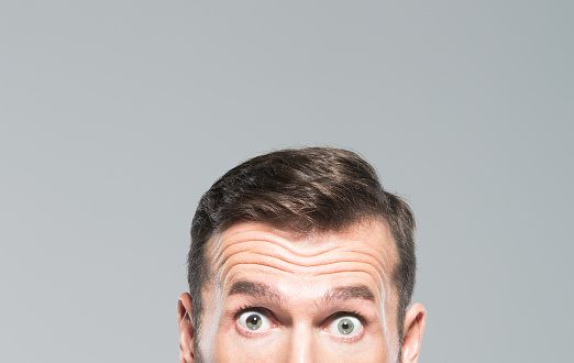 Cropped shot of mid adult man with surprised expression. Half face of mature man with eyes wide open.