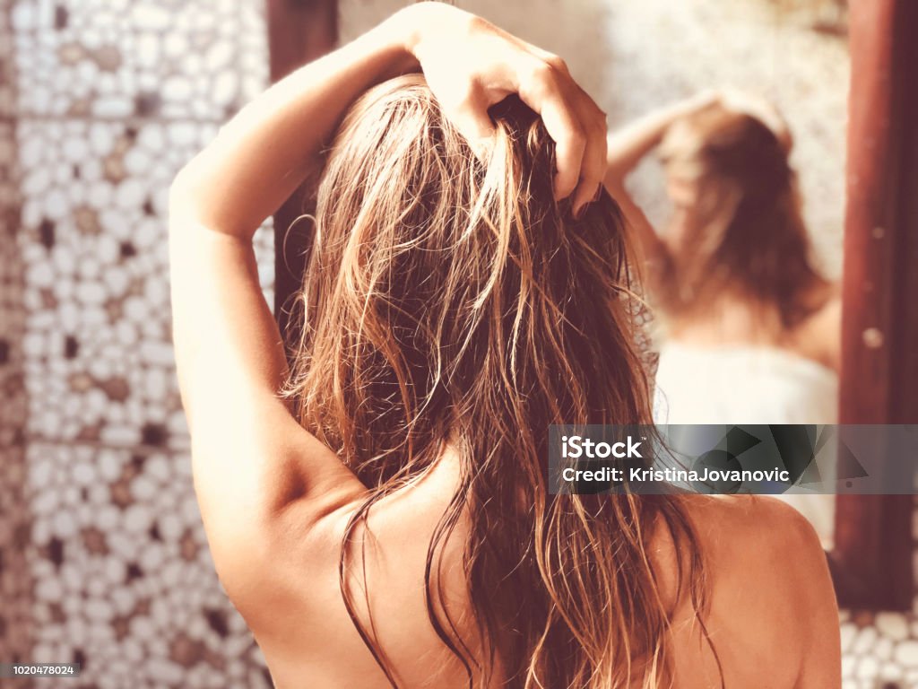 美しい女性の浴室内の鏡を見ながら濡れた髪に触れます。 - 髪のロイヤリティフリーストックフォト