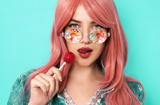 Young woman with kaleidoscope sunglasses holding lollipop