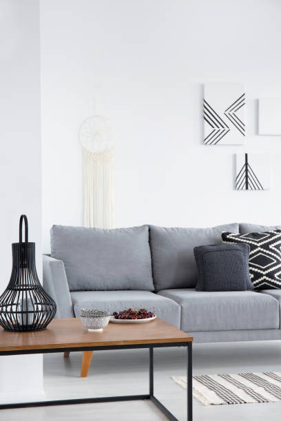 istock Pillows on grey couch and lanterns on table in minimal living room interior with posters. Real photo 1020481488