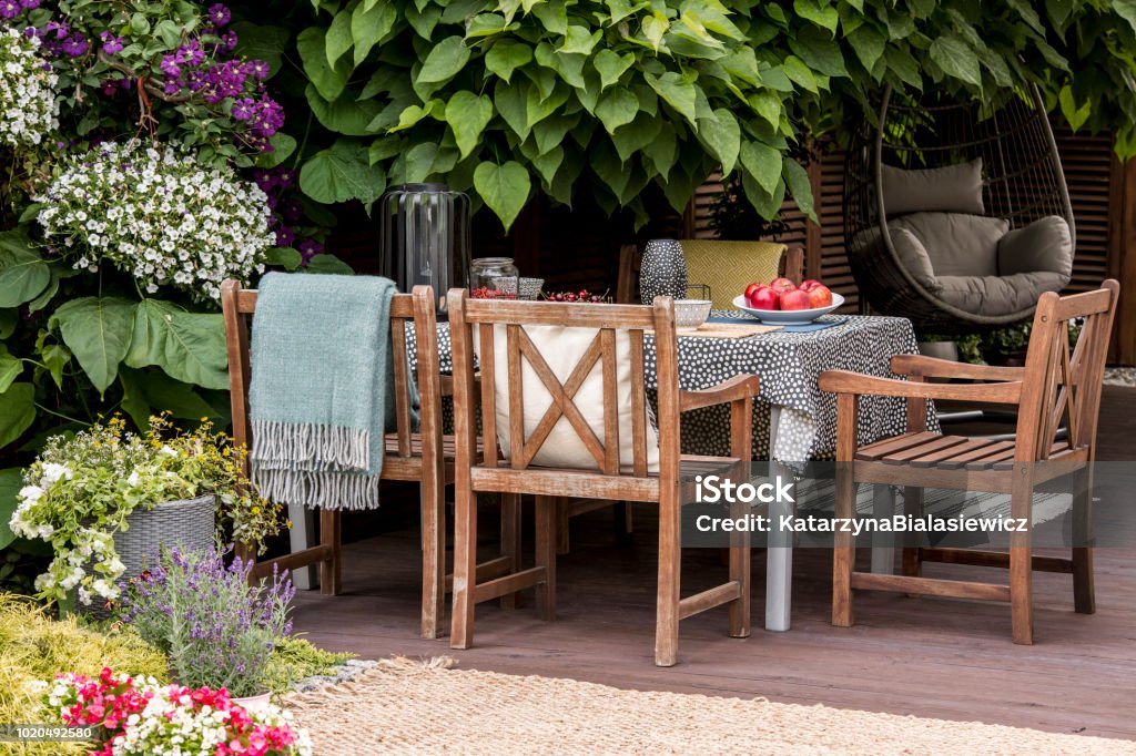 Foto real de muebles de jardín en terraza llena de flores y plantas - Foto de stock de Jardín privado libre de derechos