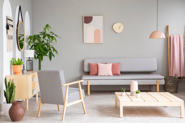 istock Patterned wooden armchair next to table in grey flat interior with poster above couch. Real photo 1020492698