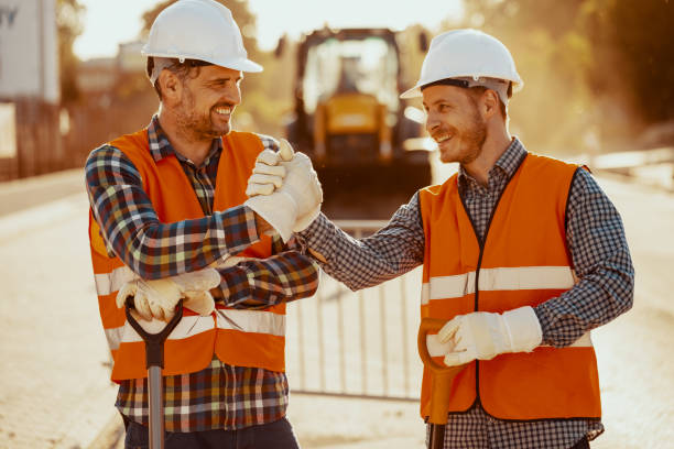 istock Smiling coworkers in reflective vests and white helmets after roadwork 1020501160
