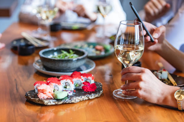 holding wine glass in sushi bar - sushi food vegetarian food japanese cuisine imagens e fotografias de stock
