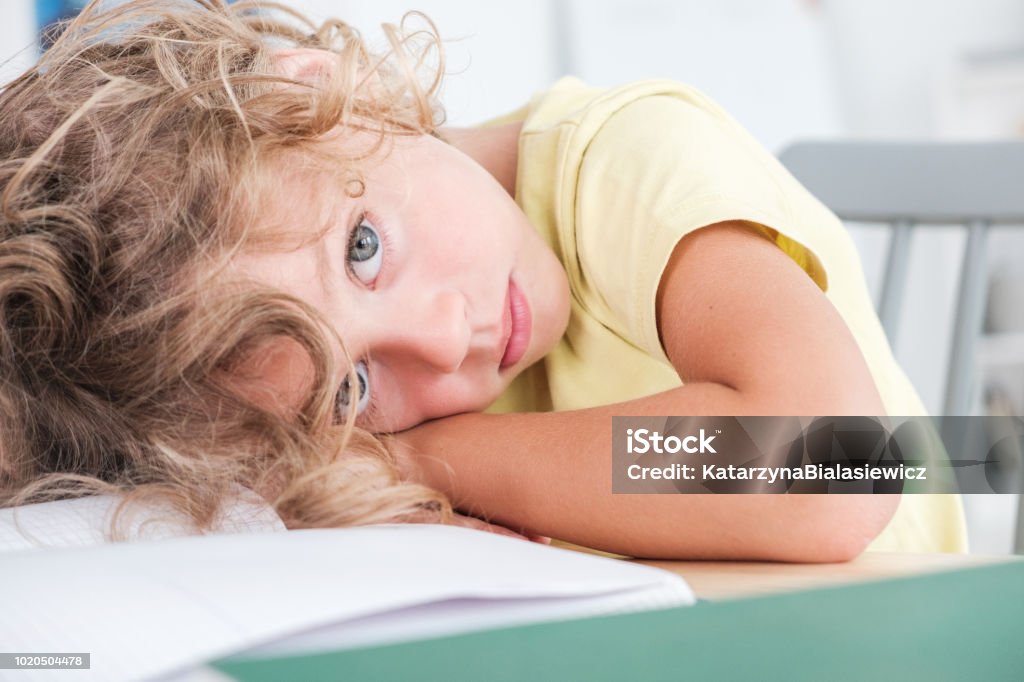 Sad and lonely kid lying his head on a desk Child Stock Photo