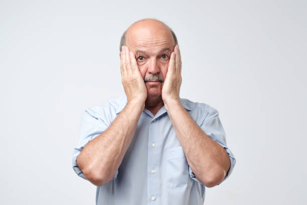istock Bald mature man with mustache in blue shirt is suffering from indecision. 1020512164