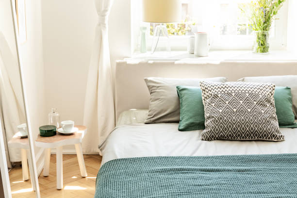 istock Pillows and green sheets on bed in bedroom interior with white table next to mirror. Real photo 1020515428