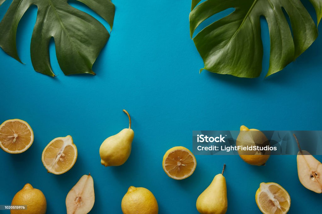 top view of palm tree leaves, pears and lemons on blue surface Antioxidant Stock Photo