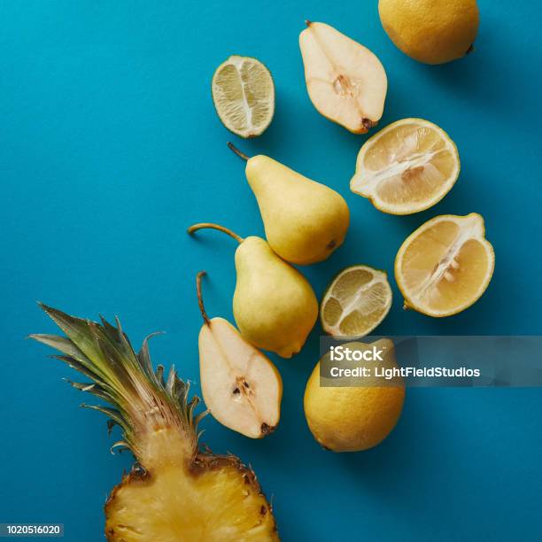 Top View Of Ripe Pineapple Pears And Lemons On Blue Surface Stock Photo - Download Image Now