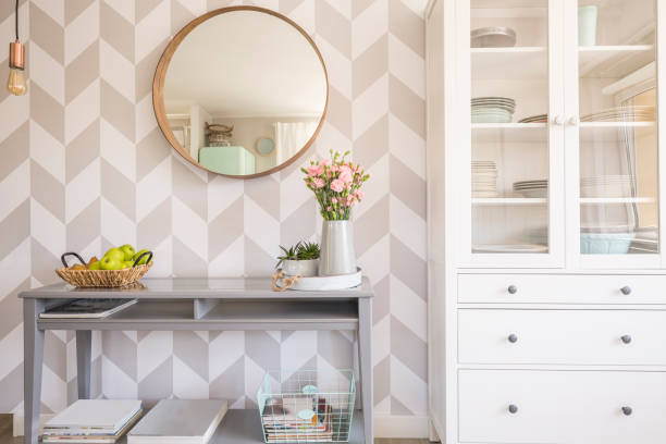 Mirror on patterned wallpaper above grey table with flowers in s stock photo