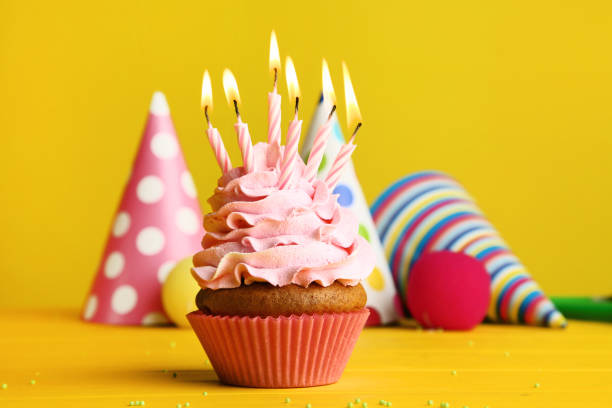 istock Cupcake with candles and paper caps on yellow background 1020519532