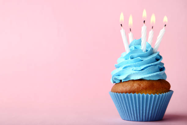 istock Tasty cupcake with candles on pink background 1020519648