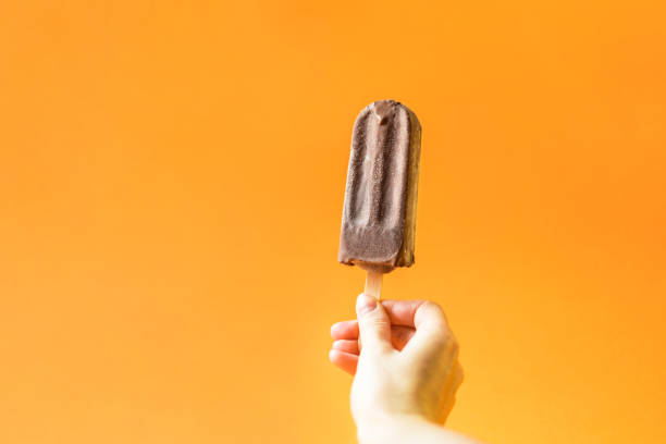 istock Hand holding chocolate ice cream on a bright orange background. 1020519854
