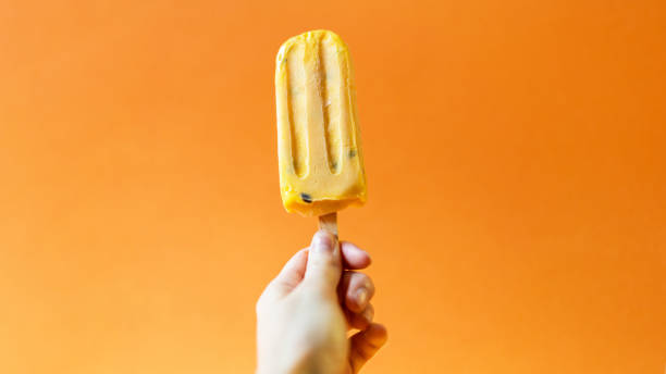 istock Hand holding mango ice cream on a bright orange background. 1020519904