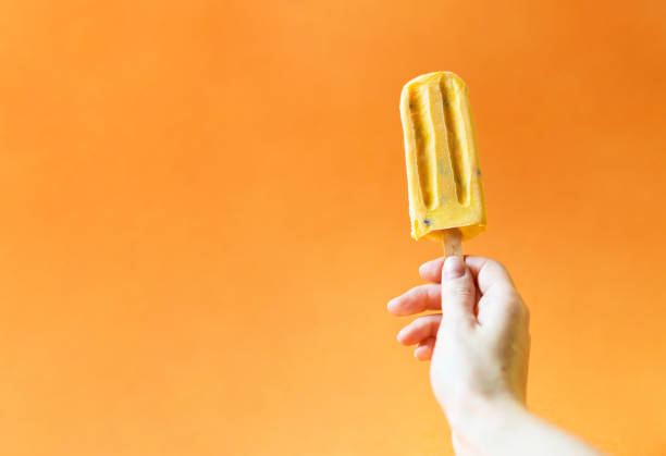 istock Mango ice cream in a girl's hand on a bright orange background. 1020519920
