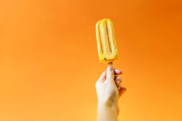 istock Girl's hand holding mango ice cream on a bright orange background. 1020520000