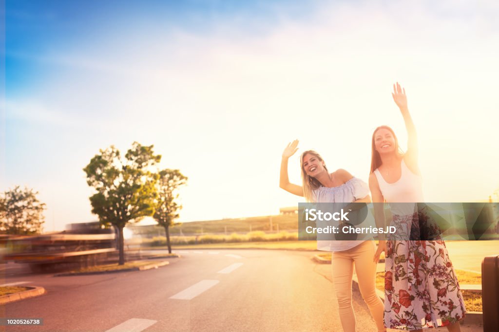 Urban hipster girls hitchhiking on roadside Two friends on a road trip, hipster girls hitchhiking on roadside of highway Car Stock Photo