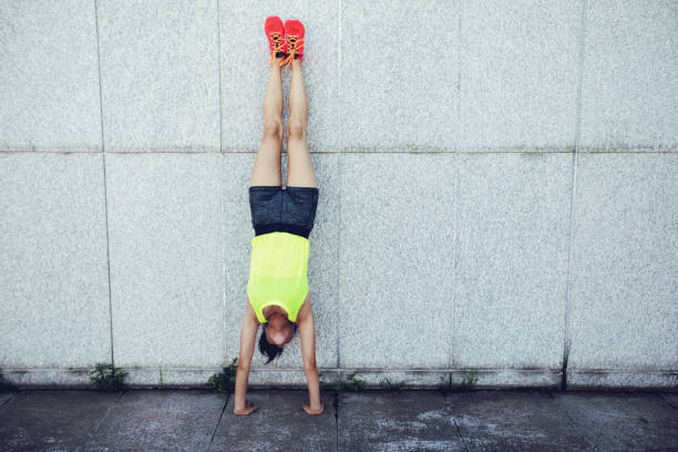 Sportswoman doing a handstand against a marble wall