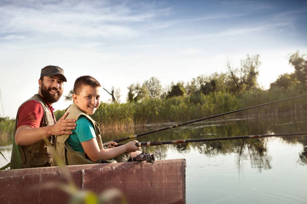Dad and son fishing from boat on river