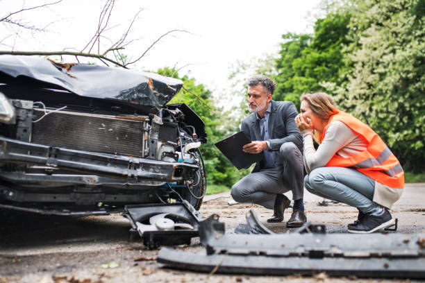 un agente de seguros y un conductor de mujer mirando el coche en la carretera después de un accidente. - damaged car fotografías e imágenes de stock