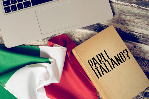 A computer, flag of Italy and book titled Speak Italian