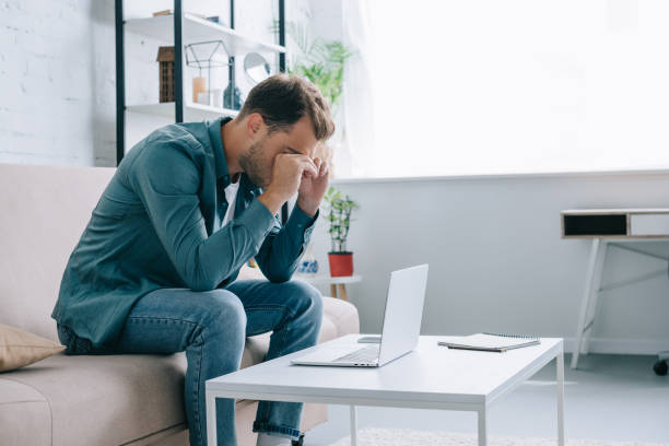 istock young man rubbing eyes while working with laptop at home 1020548314