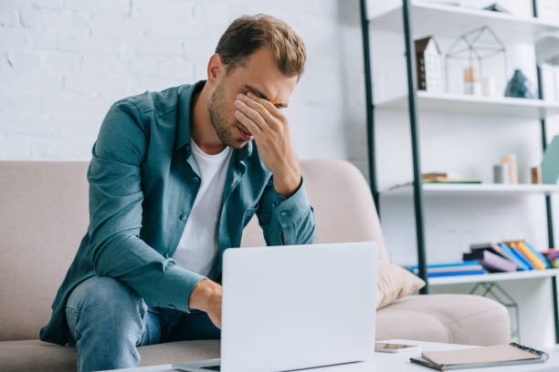istock young man with pain in eyes using laptop at home 1020548340