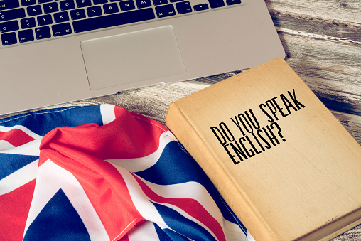 A computer, flag of Great Britain and book titled Speak English