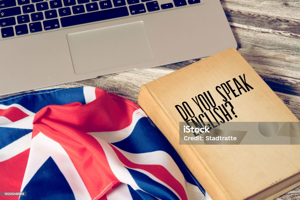 A computer, flag of Great Britain and book titled Speak English English Language Stock Photo