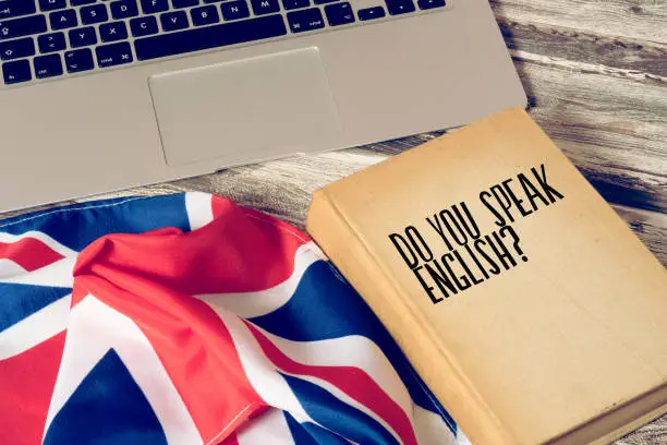 Photo of A computer, flag of Great Britain and book titled Speak English