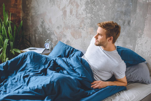 istock confident young man waking up in his bed during morning time at home 1020557822
