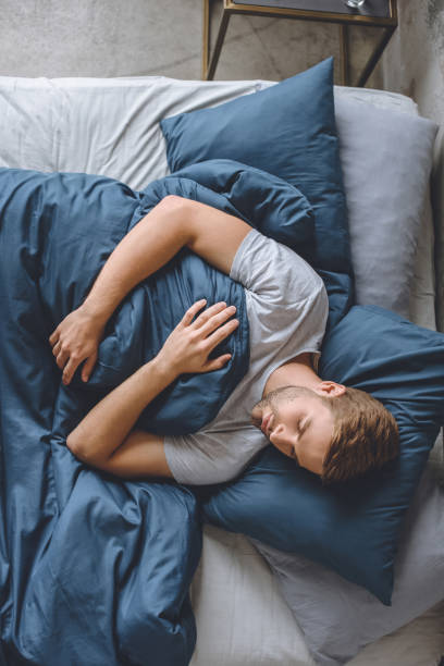 istock overhead view of young handsome man sleeping under blanket in his bed at home 1020557836