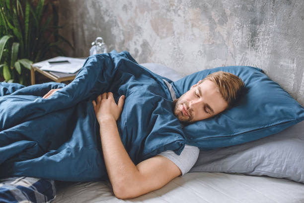 istock young handsome man sleeping under blanket in his bed at home 1020557858