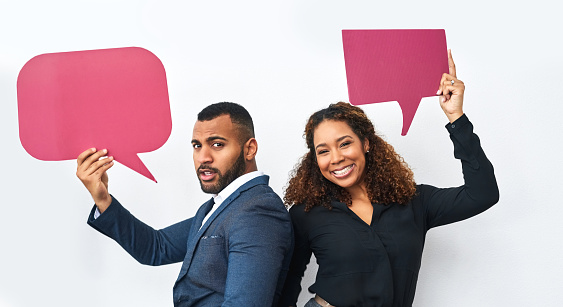 Studio shot of a young businessman and businesswoman holding speech bubbles