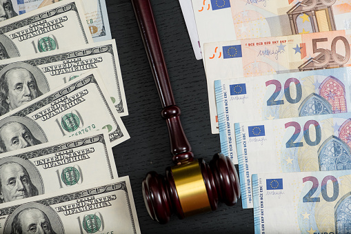Judge's gavel on the background of euro and dollar bills on wooden background