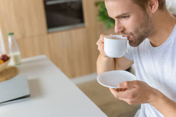istock selective focus of young man drinking coffee at kitchen 1020562948