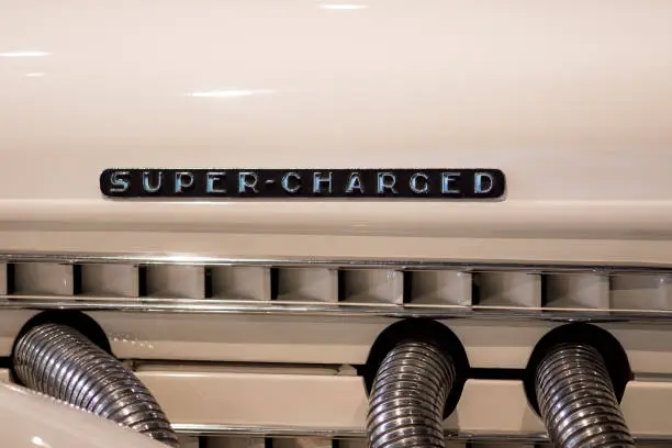 Super-charged. Retro engine mock-up with the words super charged. Cream paint and chrome pipes with 1930s design art deco sign writing.