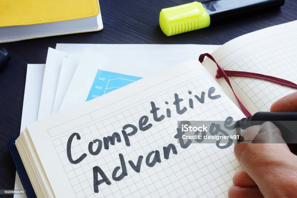 Man is writing words Competitive advantage in the notepad. Competition Stock Photo