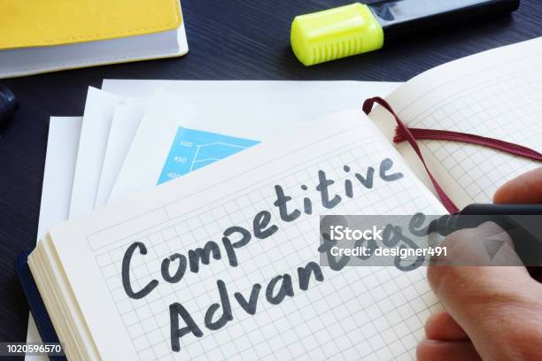 Man Is Writing Words Competitive Advantage In The Notepad Stock Photo - Download Image Now