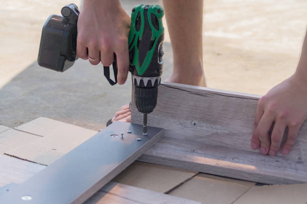 istock furniture assembling - Carpentry screws for a knock down wooden table. Electric screw driwer in workers hands 1020600628