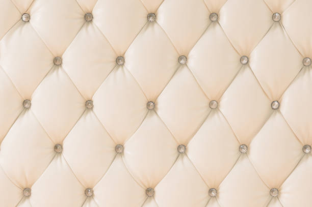 istock Beige soft tapestry pattern background with symmetrical buttons on the corners of diamonds. Soft and expensive furniture elements. Luxury background 1020605354