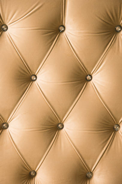 istock Beige soft textile background with symmetrical buttons on the corners of diamonds. Soft and expensive furniture elements. Luxury background 1020605728