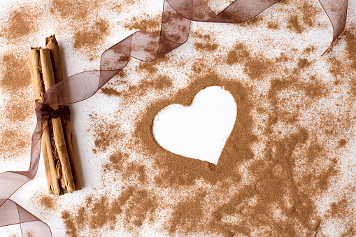 Close-up cinnamon sticks and a heart shaped on a white background. Wide space for additional text