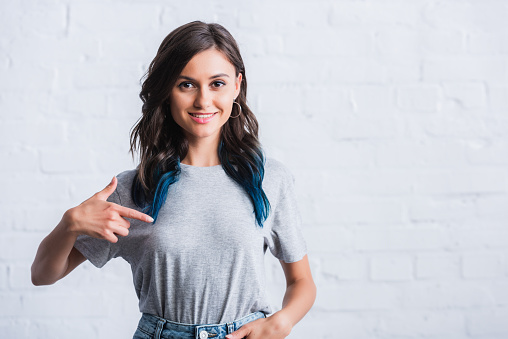 portrait of young woman pointing by finger on empty grey t-shirt
