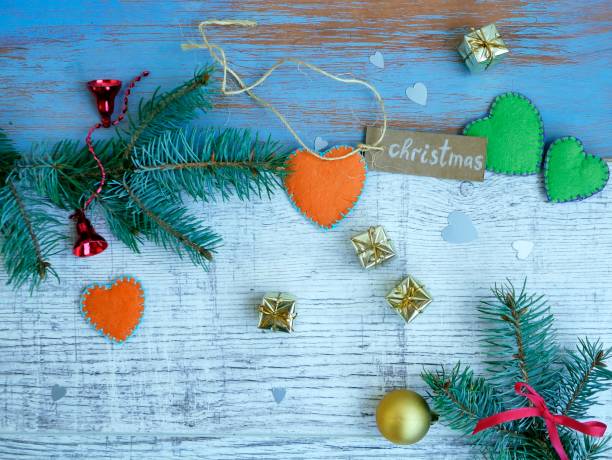 Christmas, white and blue wooden background, spruce branches, small gold gifts and handmade hearts